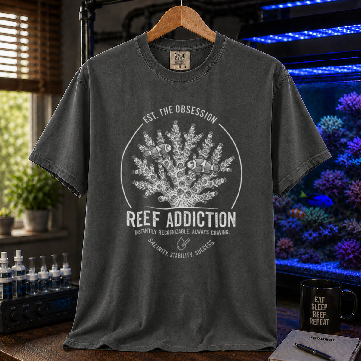 Broke Reefers saltwater aquarium graphic t-shirt featuring a circular emblem with coral, clownfish, and text: EST. THE OBSESSION, REEF ADDICTION, INSTANTLY RECOGNIZABLE. ALWAYS CRAVING, SALINITY. STABILITY. SUCCESS., khaki crew neck tee