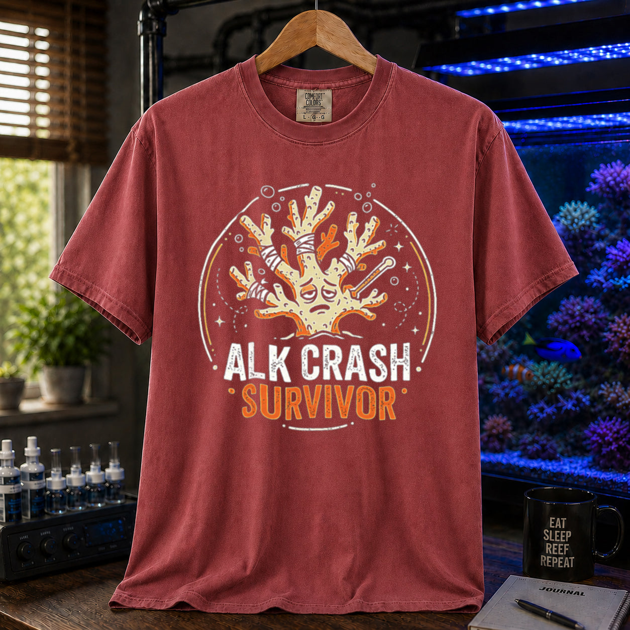 Saltwater aquarium graphic t-shirt featuring a cartoon illustration of a bandaged coral and text: ALK CRASH SURVIVOR, maroon crew neck tee