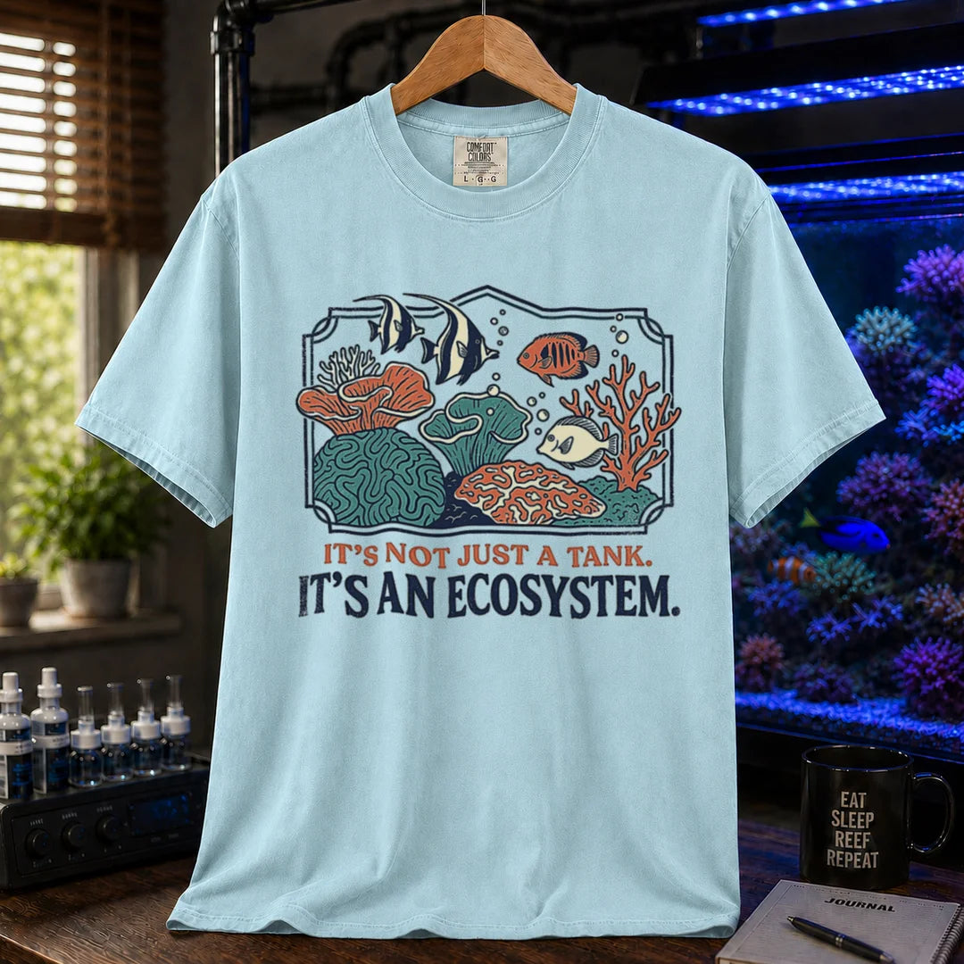 Saltwater aquarium graphic t-shirt featuring a framed biotope illustration and text: IT'S NOT JUST A TANK. IT'S AN ECOSYSTEM., light blue crew neck tee