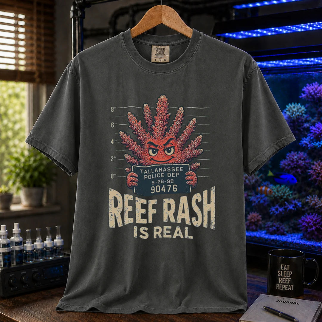 Saltwater aquarium graphic t-shirt featuring a mugshot of an anthropomorphic coral holding a police booking sign with text: REEF RASH IS REAL, dark grey crew neck tee