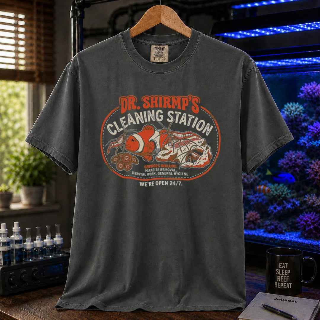 Saltwater aquarium graphic t-shirt featuring a retro badge with cleaner shrimp and text: DR. SHRIMP'S CLEANING STATION SERVICES INCLUDE: PARASITE REMOVAL, DENTAL WORK, GENERAL HYGIENE WE'RE OPEN 24/7., dark grey crew neck tee