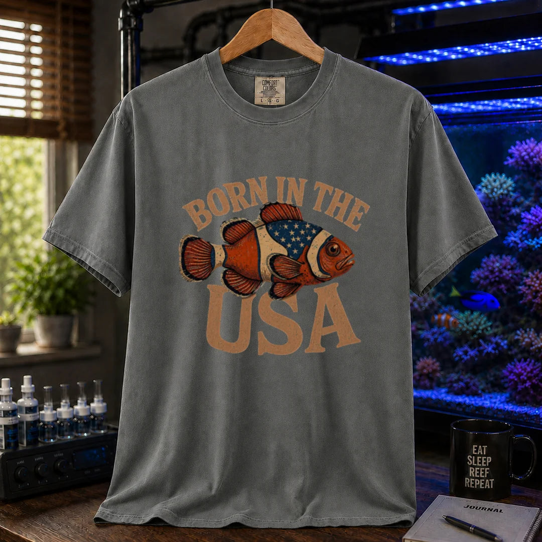 Saltwater aquarium graphic t-shirt featuring distressed vintage typography reading Born in the USA with an illustrated clownfish patterned like the American flag, dark grey crew neck tee