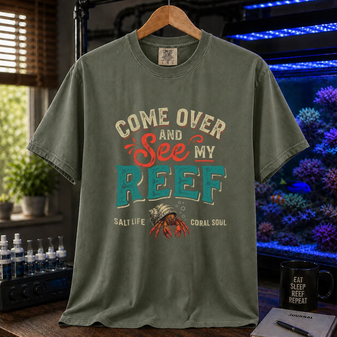 Saltwater aquarium graphic t-shirt featuring distressed retro typography reading Come Over And See My Reef with a hermit crab illustration and footer text, military green crew neck tee