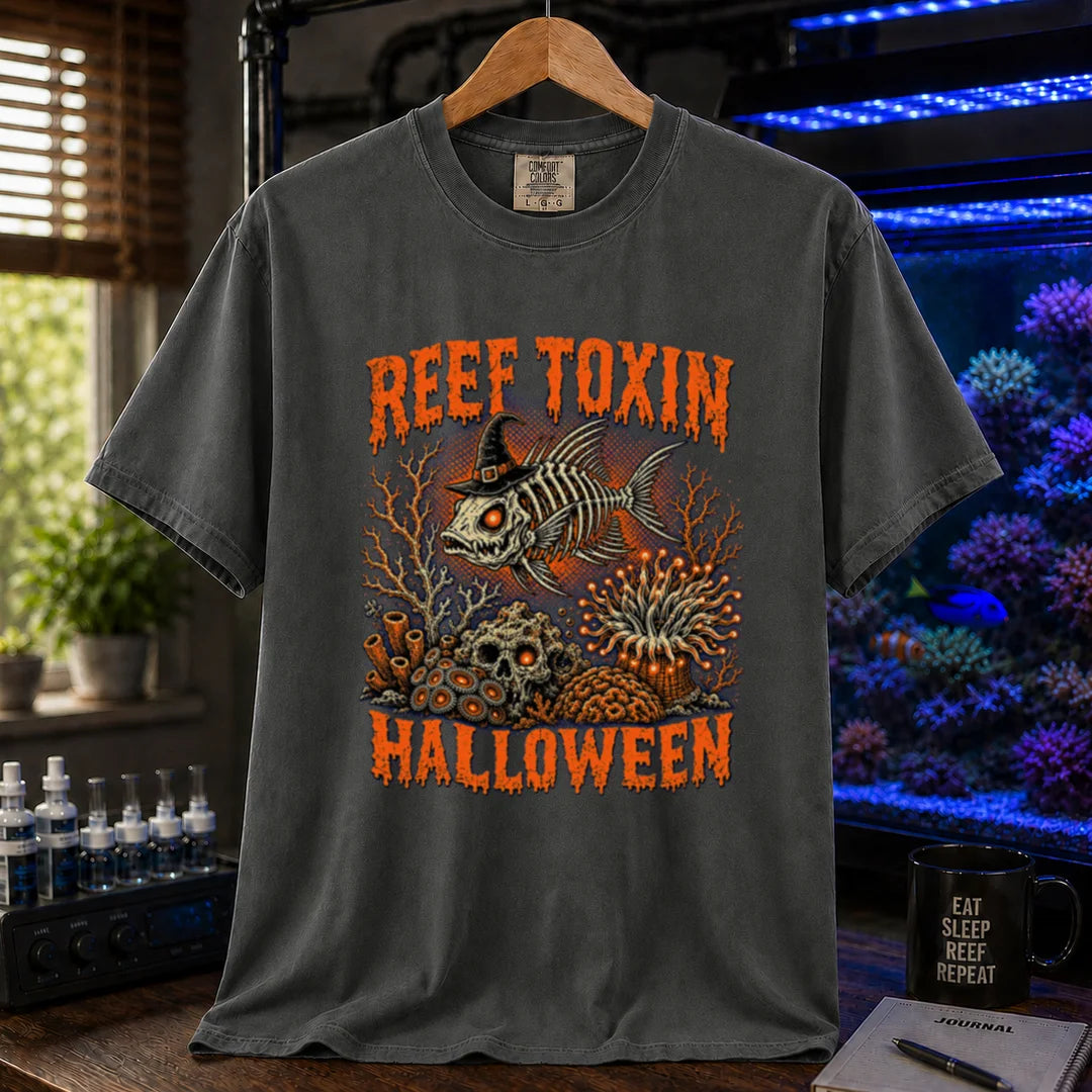 Saltwater aquarium graphic t-shirt design featuring dripping orange typography reading Reef Toxin Halloween with a witch-hat-wearing fish skeleton, glowing zoanthids, a skull in the rocks, and an anemone, dark grey crew neck tee