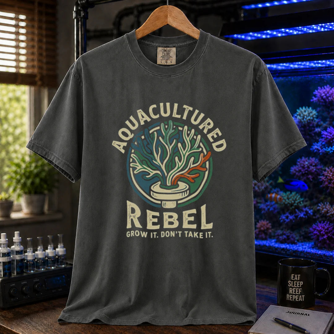 Saltwater aquarium graphic t-shirt design featuring a vintage badge reading Aquacultured Rebel Grow It. Don't Take It. with a coral frag plug illustration on a dark grey tee