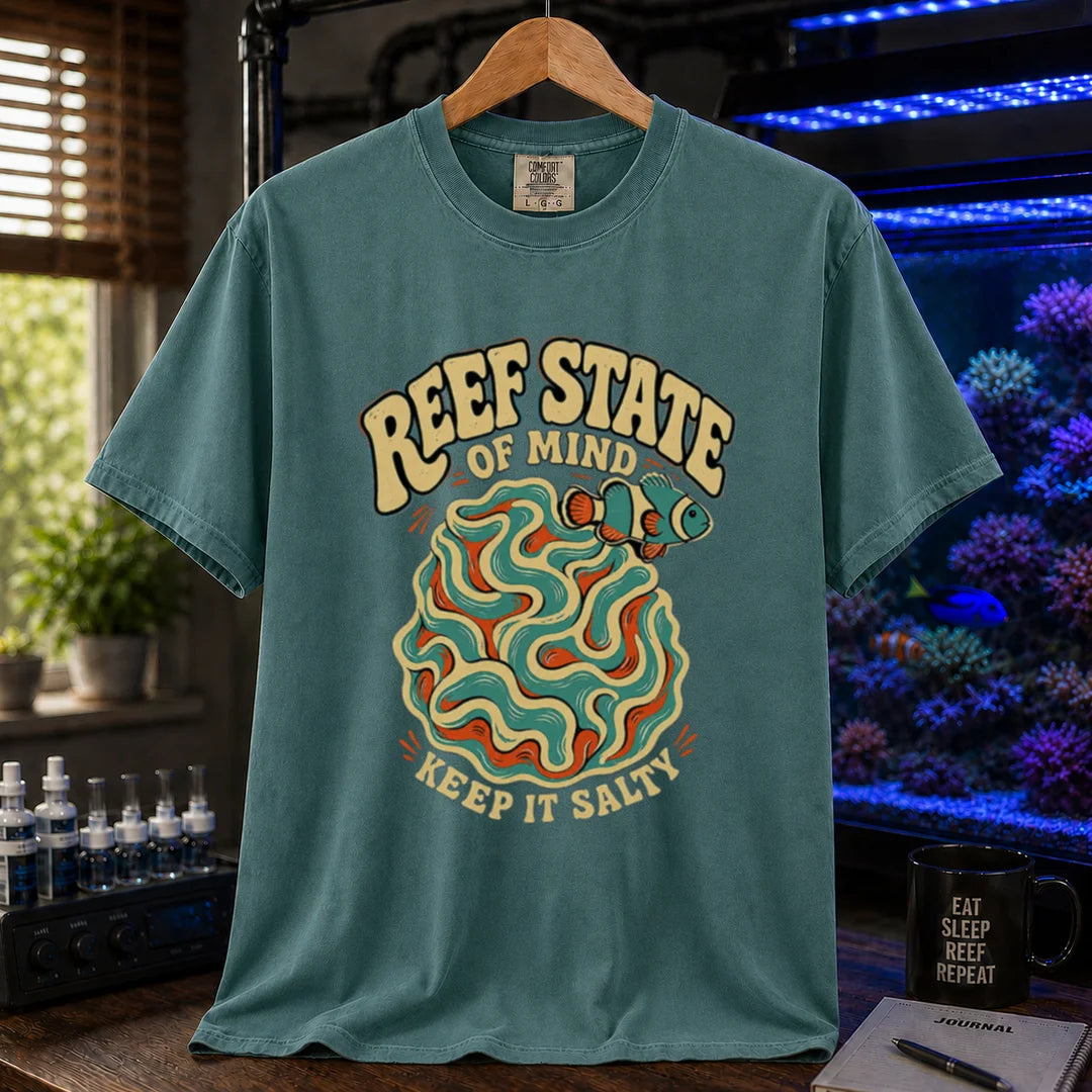Saltwater aquarium graphic t-shirt featuring retro cream typography reading Reef State Of Mind Keep It Salty with a swirling abstract coral and clownfish design printed on a green tee displayed in a reef room setting