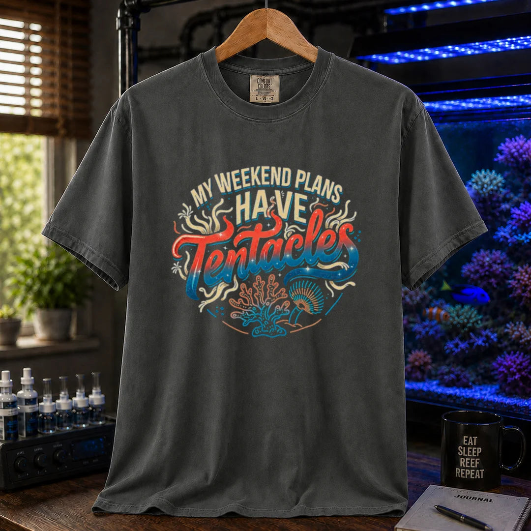 Saltwater aquarium graphic t-shirt featuring distressed cream, turquoise, and red gradient typography reading My Weekend Plans Have Tentacles with coral and polyp graphics printed on a dark grey tee displayed in a reef room setting