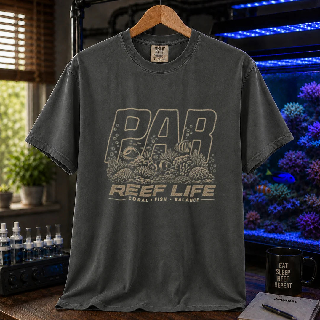 Saltwater aquarium graphic t-shirt featuring distressed cream typography reading PAR and Reef Life with an intricate engraved reef, coral, and fish illustration printed on a dark grey tee displayed in a reef room setting