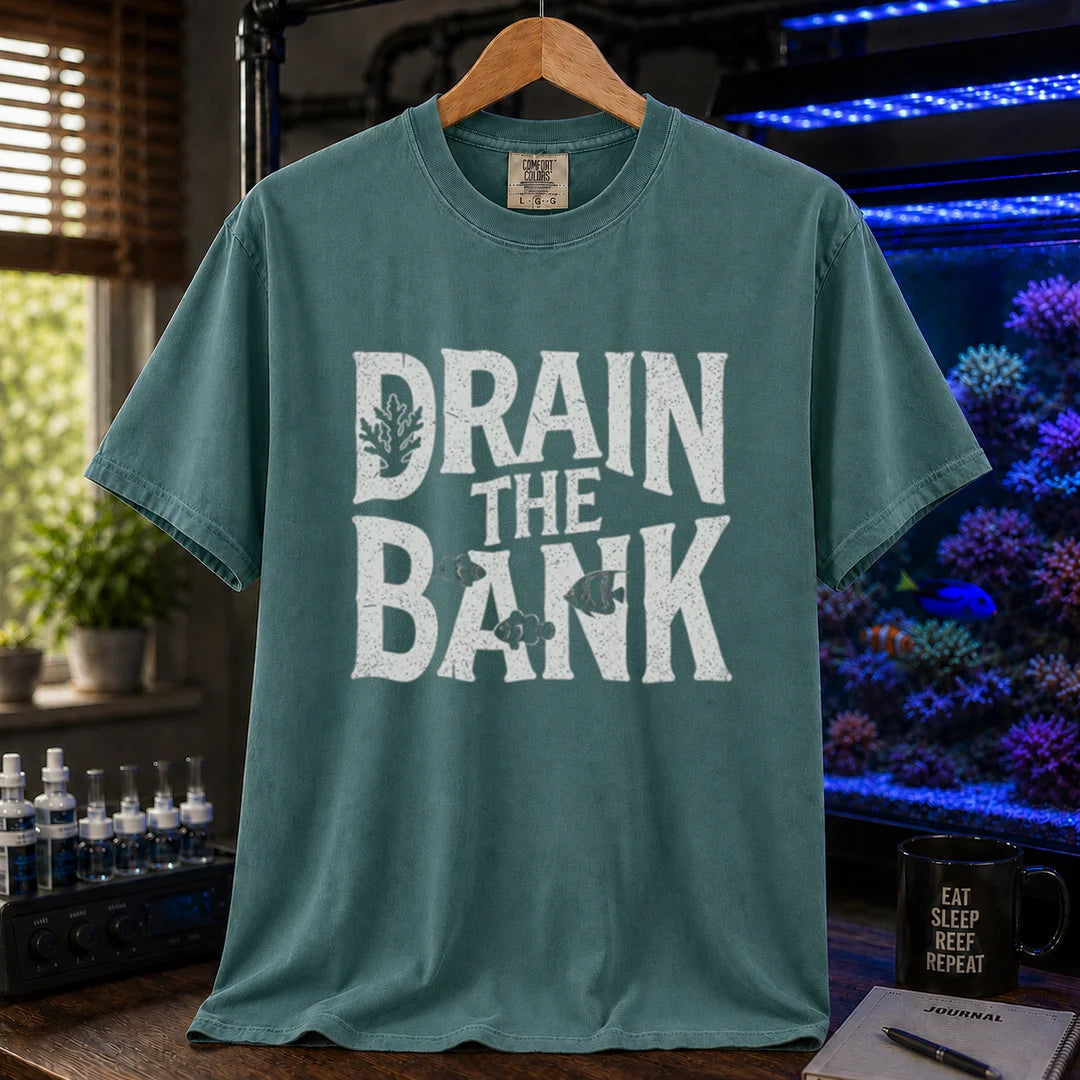 Saltwater aquarium graphic t-shirt featuring distressed white block lettering reading Drain The Bank with subtle fish and coral shapes on a green shirt
