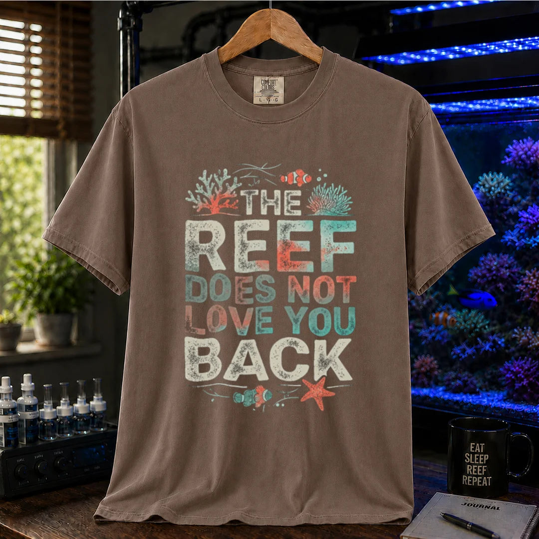 Saltwater aquarium graphic t-shirt featuring distressed multi-row typography reading The Reef Does Not Love You Back with coral and clownfish illustrations on a brown shirt