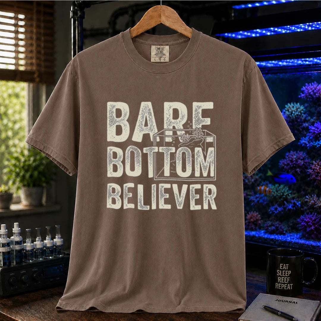 Saltwater aquarium graphic t-shirt featuring distressed typography reading Bare Bottom Believer with an aquarium outline illustration on a brown shirt