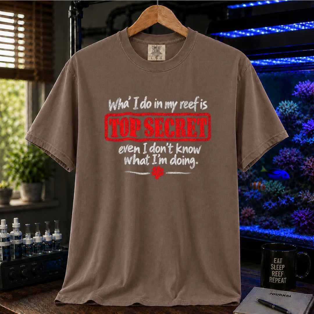 Saltwater aquarium graphic t-shirt featuring distressed typography reading What I do in my reef is Top Secret even I don't know what I'm doing with a red stamp effect on a brown shirt