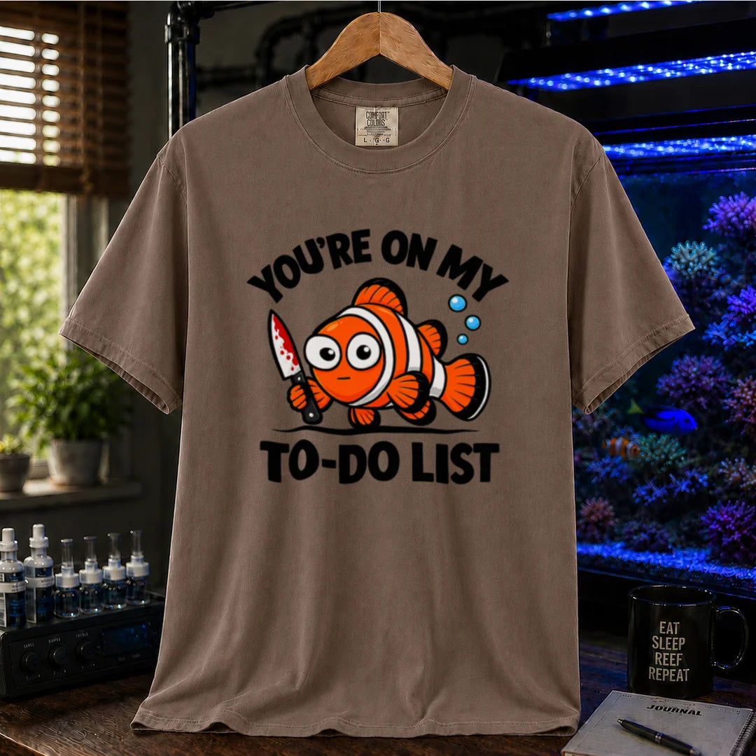 Saltwater aquarium graphic t-shirt featuring bold typography reading You're On My To-Do List framing an illustration of a clownfish holding a knife on a brown shirt