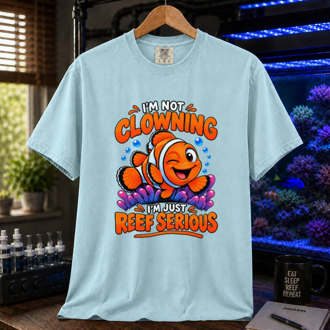 Saltwater aquarium graphic t-shirt featuring bold typography reading I'm Not Clowning I'm Just Reef Serious with a winking clownfish illustration on a light blue T-Shirt