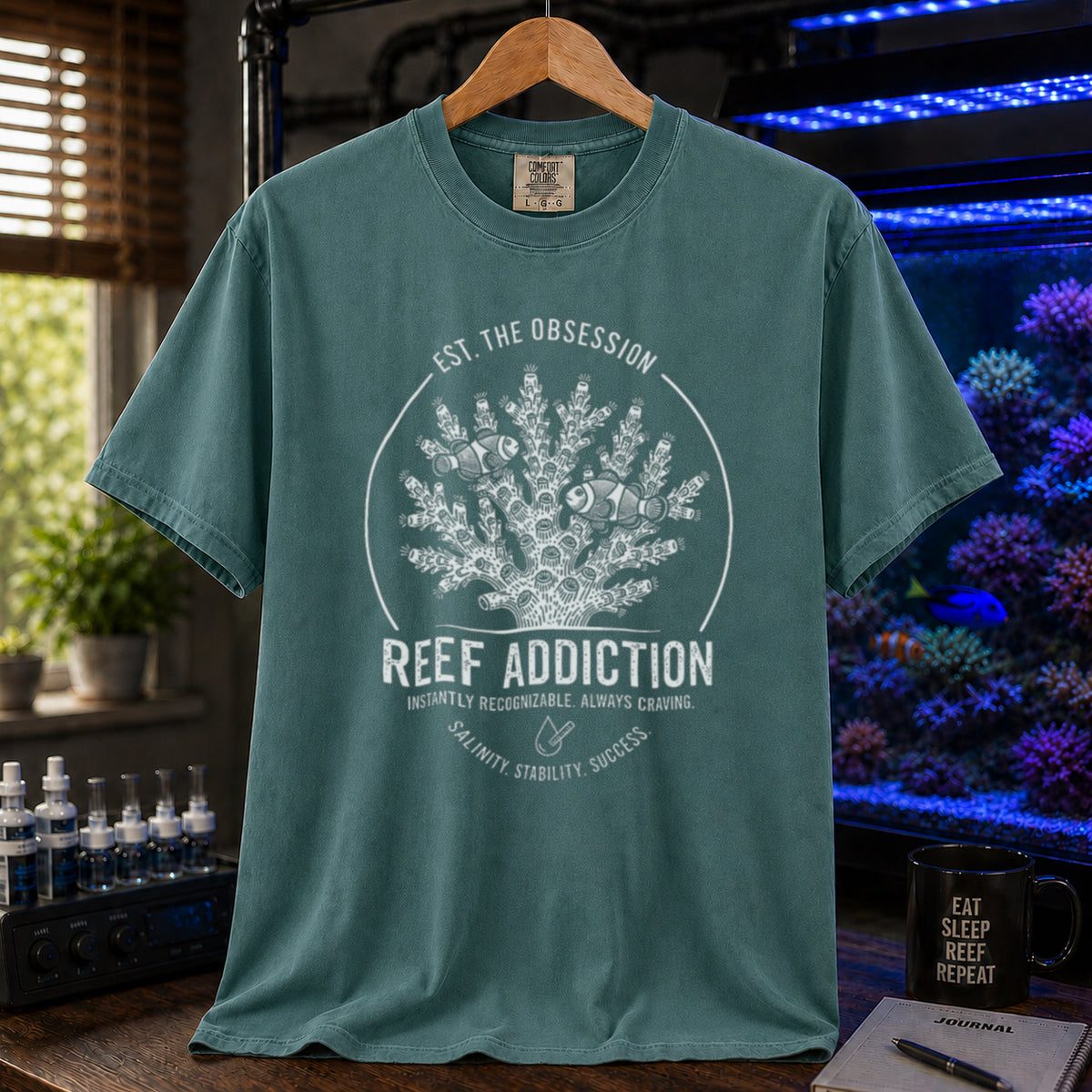 Broke Reefers saltwater aquarium graphic t-shirt featuring a circular emblem with coral, clownfish, and text: EST. THE OBSESSION, REEF ADDICTION, INSTANTLY RECOGNIZABLE. ALWAYS CRAVING, SALINITY. STABILITY. SUCCESS., green crew neck tee