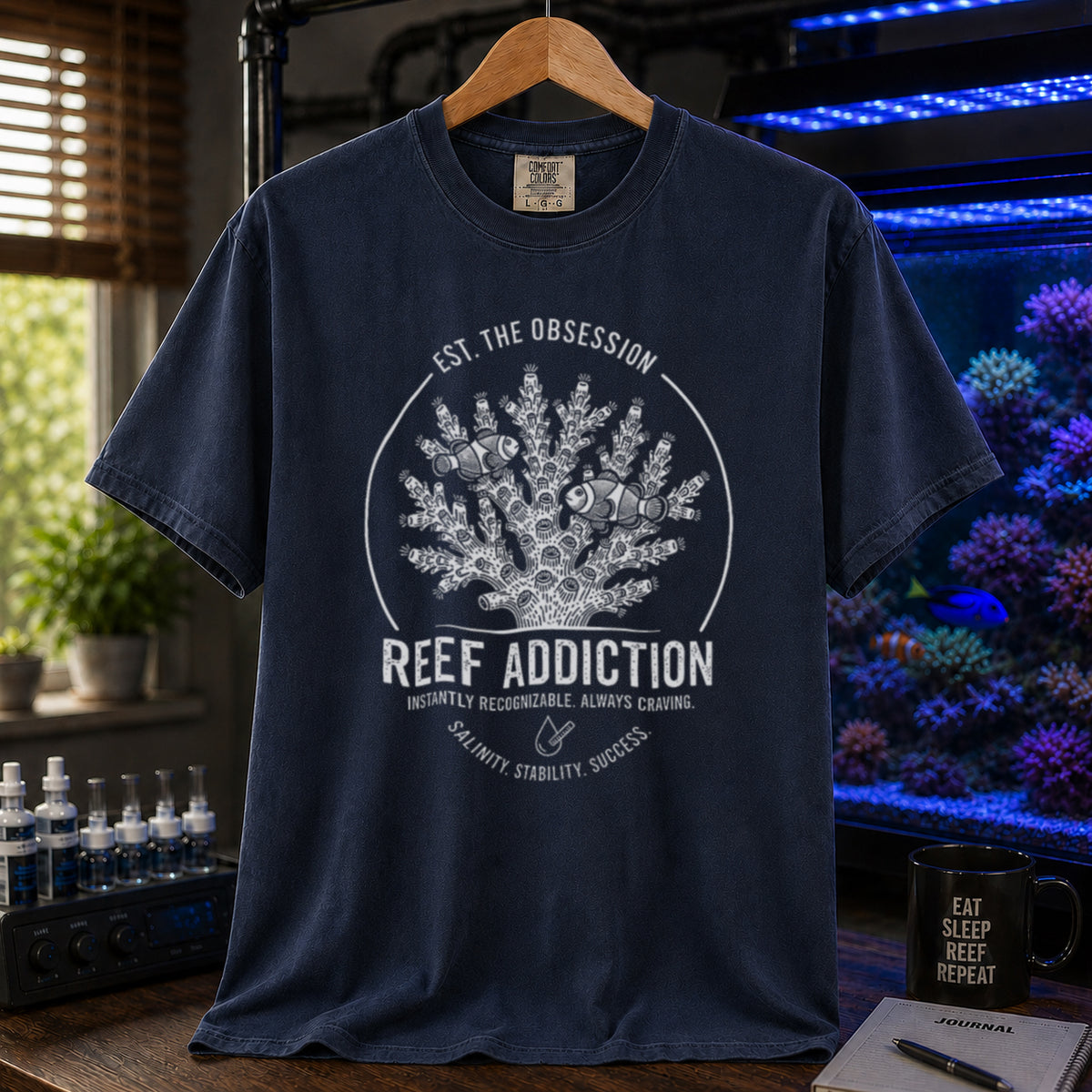 Broke Reefers saltwater aquarium graphic t-shirt featuring a circular emblem with coral, clownfish, and text: EST. THE OBSESSION, REEF ADDICTION, INSTANTLY RECOGNIZABLE. ALWAYS CRAVING, SALINITY. STABILITY. SUCCESS., navy crew neck tee
