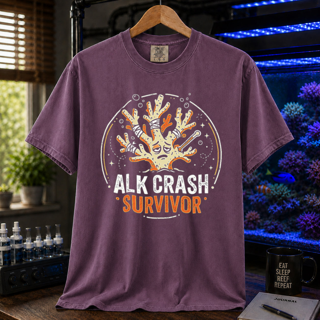 Saltwater aquarium graphic t-shirt featuring a cartoon illustration of a bandaged coral and text: ALK CRASH SURVIVOR, purple crew neck tee