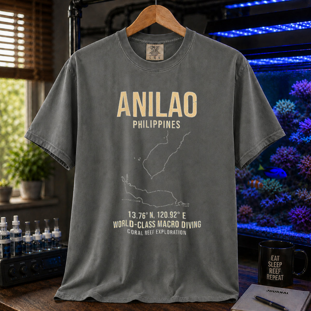 Saltwater aquarium graphic t-shirt featuring a map outline of Anilao, Philippines, coordinates, and the text: ANILAO PHILIPPINES, 13.76 N, 120.92 E, WORLD-CLASS MACRO DIVING, CORAL REEF EXPLORATION, khaki crew neck tee