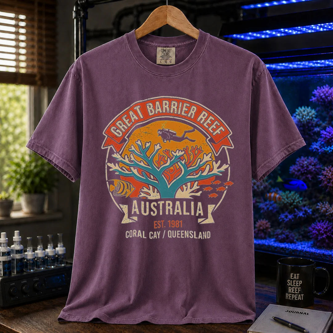 Saltwater aquarium graphic t-shirt featuring a retro colorful emblem of a scuba diver over a coral reef and text: GREAT BARRIER REEF, AUSTRALIA, EST. 1981, CORAL CAY / QUEENSLAND, purple crew neck tee
