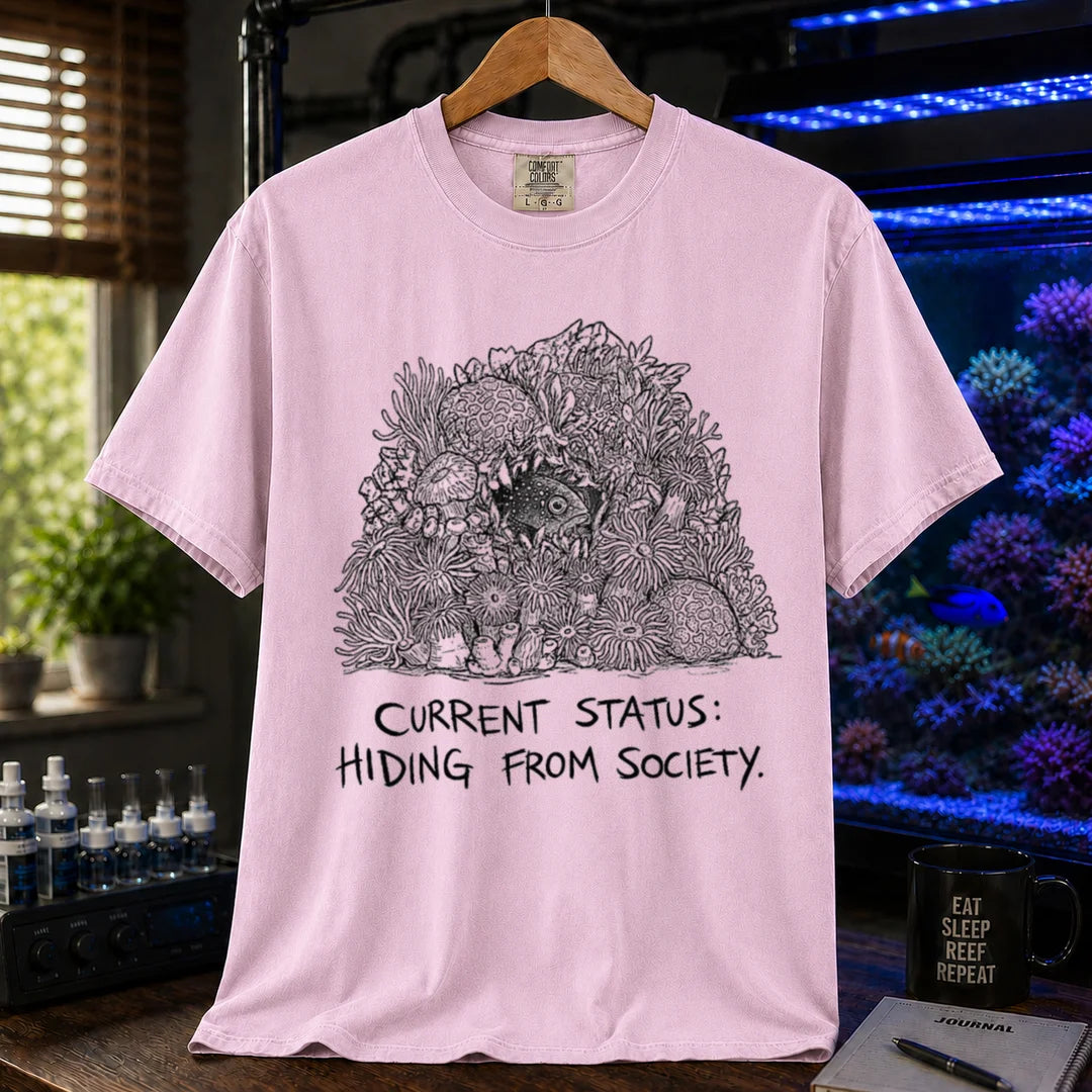 Saltwater aquarium graphic t-shirt on a pure solid white fabric background featuring an ink illustration of a fish hiding in coral and text: CURRENT STATUS: HIDING FROM SOCIETY, pink crew neck tee