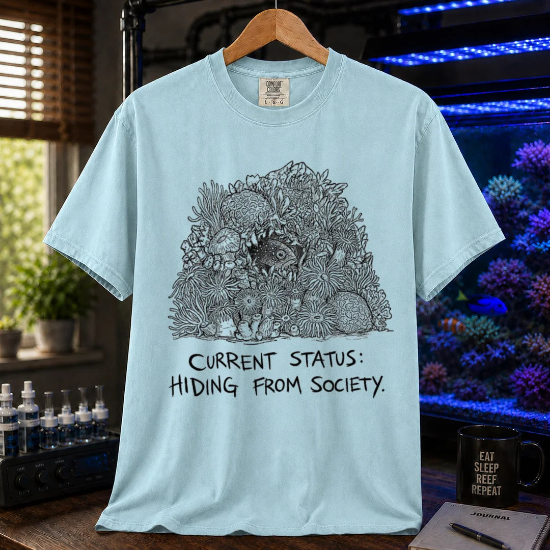 Saltwater aquarium graphic t-shirt on a pure solid white fabric background featuring an ink illustration of a fish hiding in coral and text: CURRENT STATUS: HIDING FROM SOCIETY, light blue crew neck tee