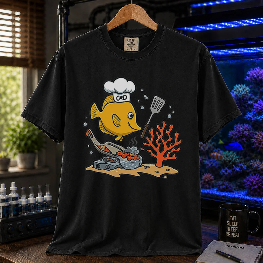 Saltwater aquarium graphic t-shirt featuring a yellow Tang wearing a chef hat and cooking with a spatula over a stove, black crew neck tee