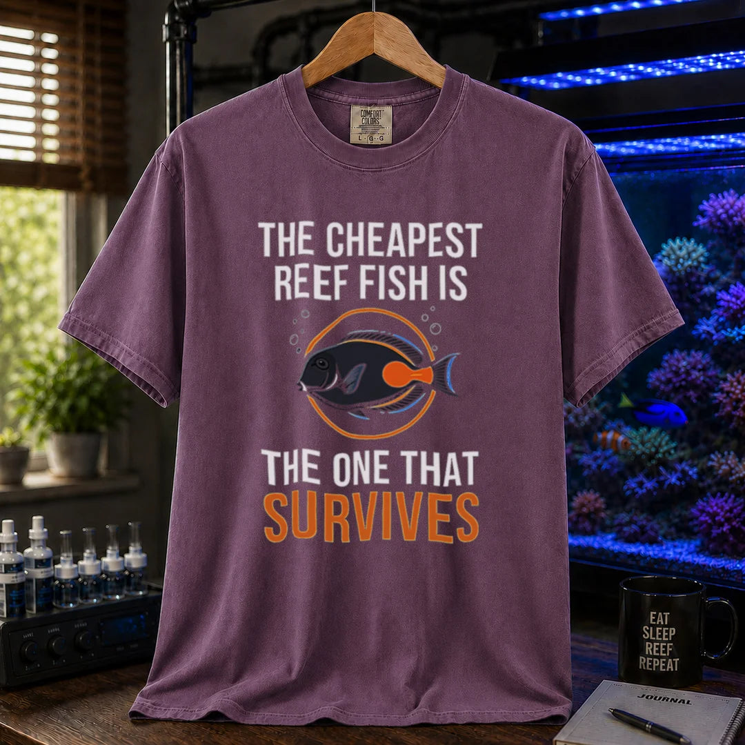 Saltwater aquarium graphic t-shirt featuring an Achilles Tang illustration inside a circular badge with text: THE CHEAPEST REEF FISH IS THE ONE THAT SURVIVES, purple crew neck tee