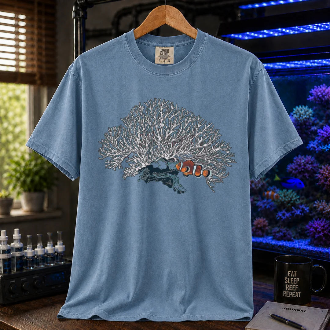 Saltwater aquarium graphic t-shirt featuring a detailed white branching coral illustration with a clownfish nestled underneath, blue crew neck tee