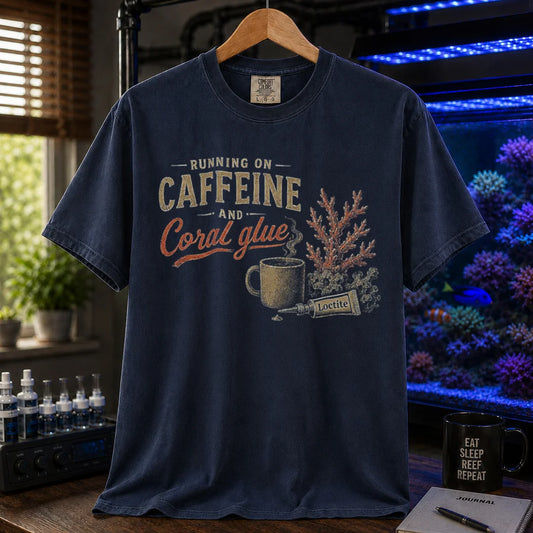 Saltwater aquarium graphic t-shirt featuring an illustration of a coffee mug, super glue, and coral with text: RUNNING ON CAFFEINE AND Coral glue, navy crew neck tee