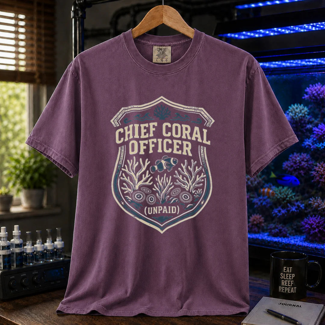 Saltwater aquarium graphic t-shirt featuring a badge illustration with text: CHIEF CORAL OFFICER (UNPAID), purple crew neck tee