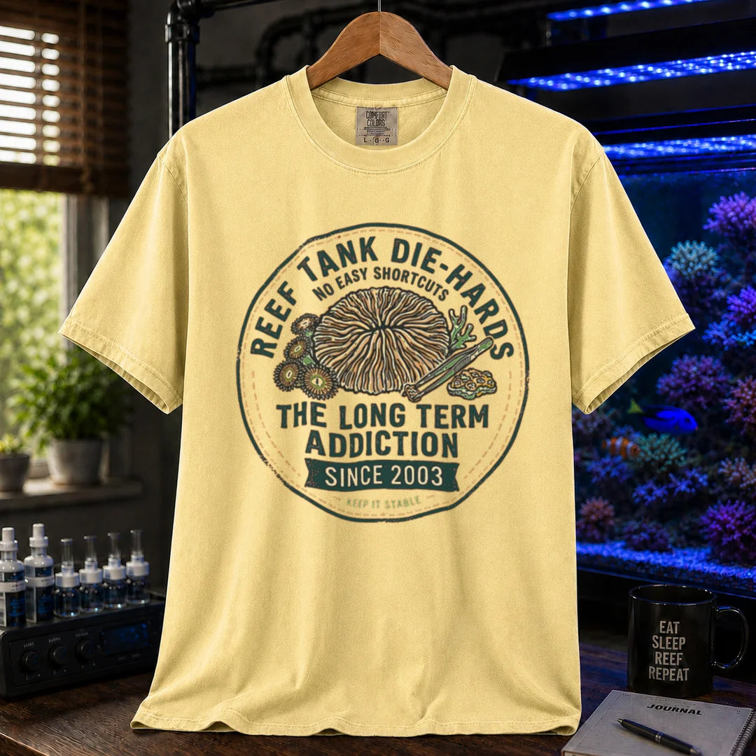 Saltwater aquarium graphic t-shirt featuring a circular vintage emblem illustration and text: REEF TANK DIE-HARDS THE LONG TERM ADDICTION SINCE 2003, yellow crew neck tee
