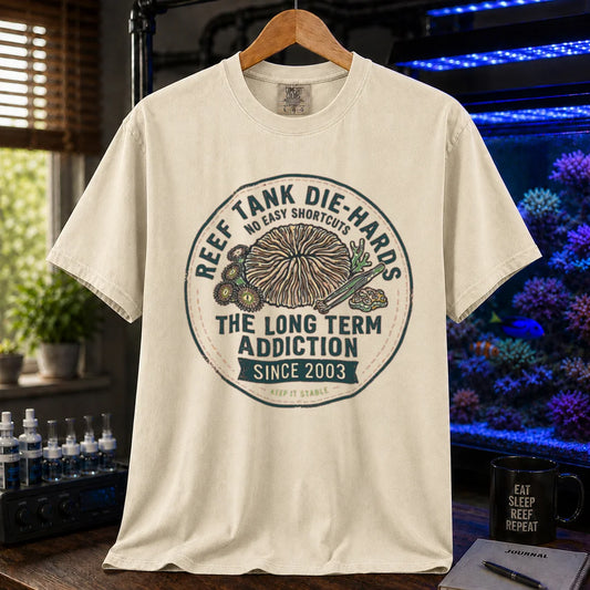 Saltwater aquarium graphic t-shirt featuring a circular vintage emblem illustration and text: REEF TANK DIE-HARDS THE LONG TERM ADDICTION SINCE 2003, cream, beige, ivory crew neck tee
