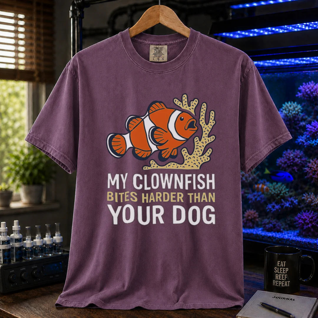 Saltwater aquarium graphic t-shirt featuring a clownfish and coral illustration with text: MY CLOWNFISH BITES HARDER THAN YOUR DOG, purple crew neck tee