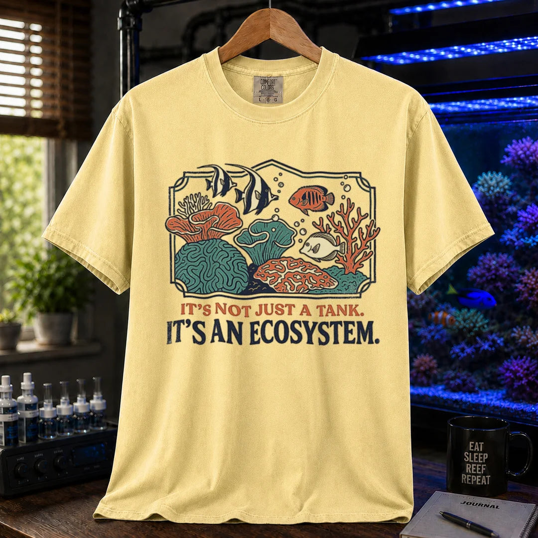 Saltwater aquarium graphic t-shirt featuring a framed biotope illustration and text: IT'S NOT JUST A TANK. IT'S AN ECOSYSTEM., yellow crew neck tee
