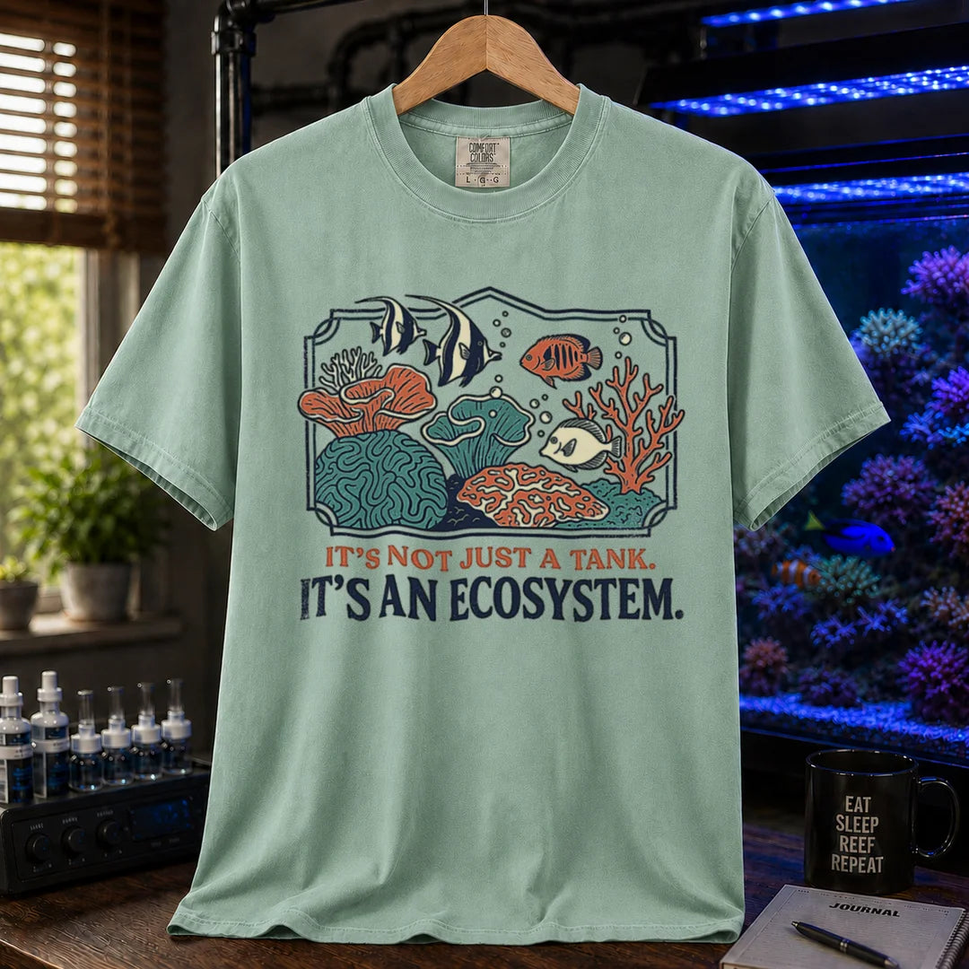 Saltwater aquarium graphic t-shirt featuring a framed biotope illustration and text: IT'S NOT JUST A TANK. IT'S AN ECOSYSTEM., green crew neck tee