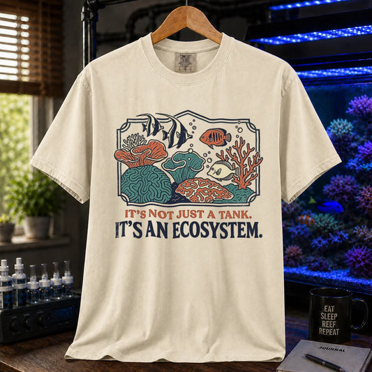 Saltwater aquarium graphic t-shirt featuring a framed biotope illustration and text: IT'S NOT JUST A TANK. IT'S AN ECOSYSTEM., cream, beige, ivory crew neck tee