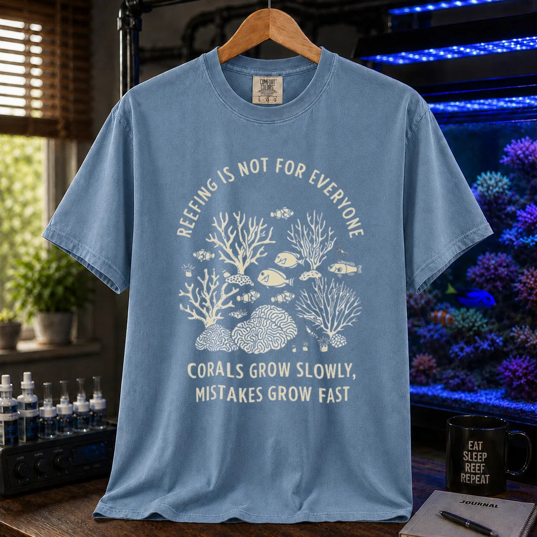 Saltwater aquarium graphic t-shirt featuring a detailed coral illustration and text: REEFING IS NOT FOR EVERYONE CORALS GROW SLOWLY, MISTAKES GROW FAST, blue crew neck tee