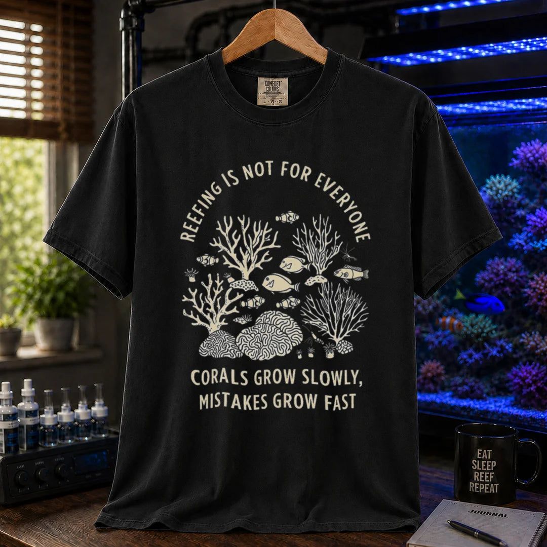 Saltwater aquarium graphic t-shirt featuring a detailed coral illustration and text: REEFING IS NOT FOR EVERYONE CORALS GROW SLOWLY, MISTAKES GROW FAST, black crew neck tee