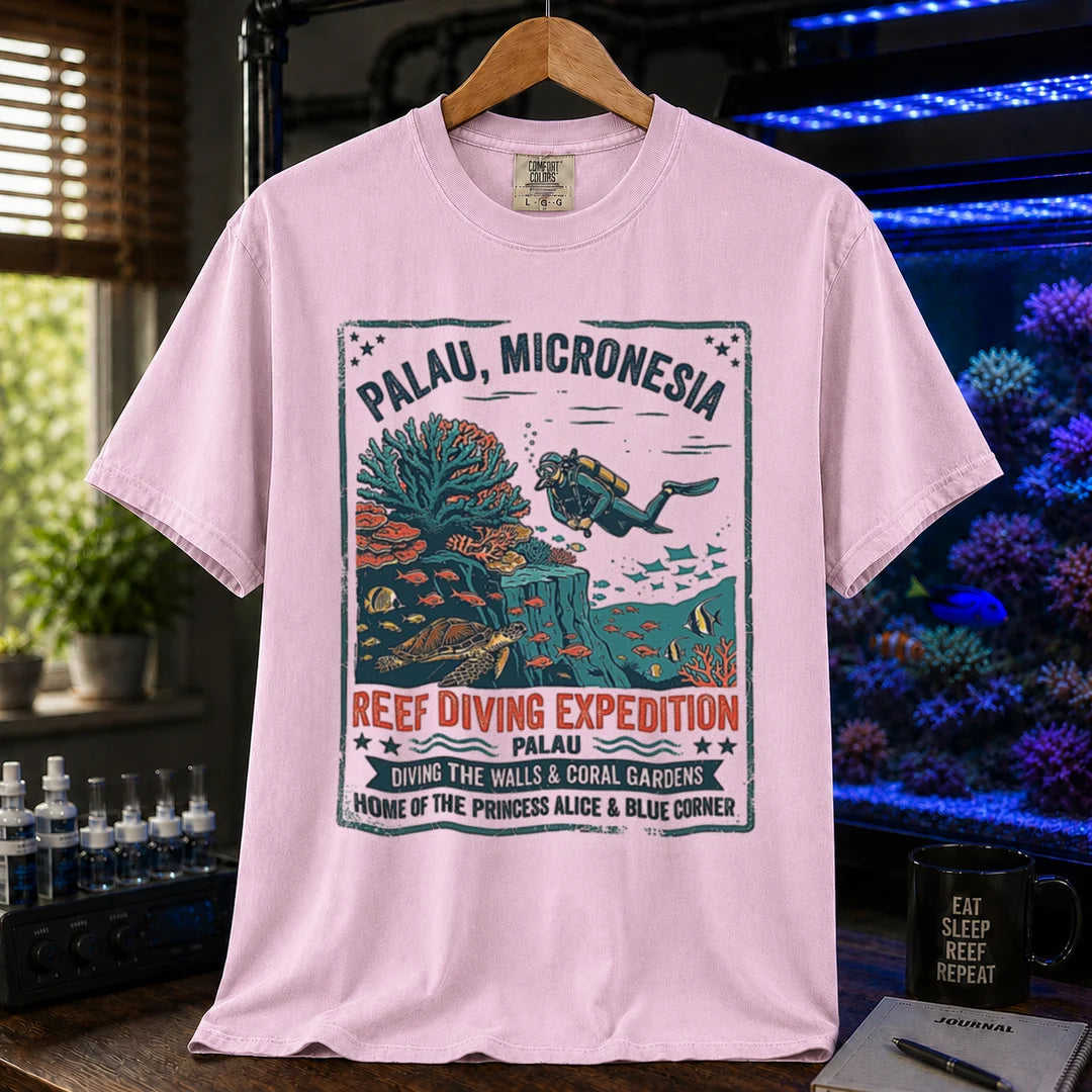 Saltwater aquarium graphic t-shirt featuring a vintage Palau diving expedition badge and text: PALAU, MICRONESIA REEF DIVING EXPEDITION, pink crew neck tee