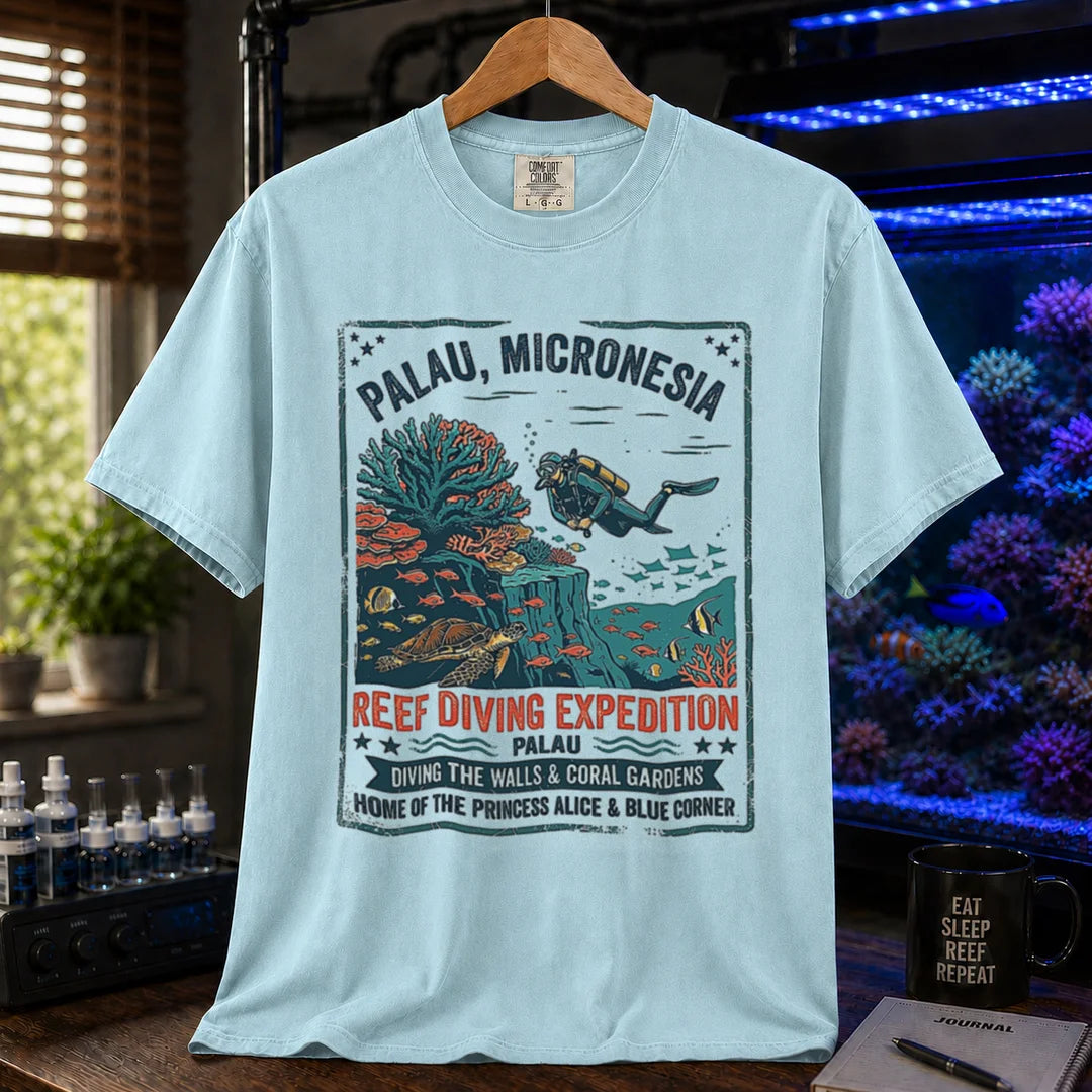 Saltwater aquarium graphic t-shirt featuring a vintage Palau diving expedition badge and text: PALAU, MICRONESIA REEF DIVING EXPEDITION, light blue crew neck tee