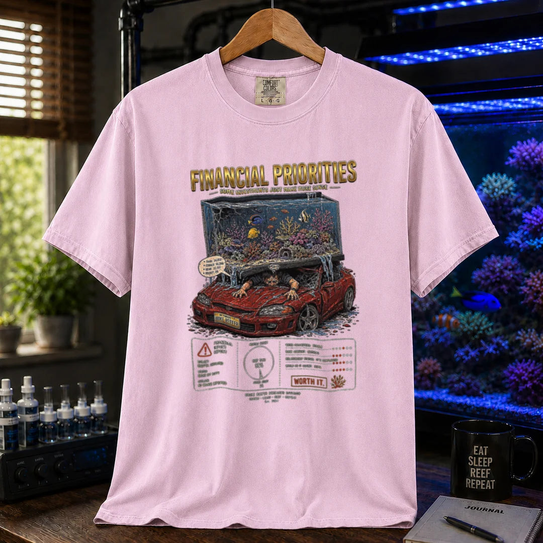 Saltwater aquarium graphic t-shirt featuring a reef tank crushing a car illustration and text: FINANCIAL PRIORITIES, pink crew neck tee