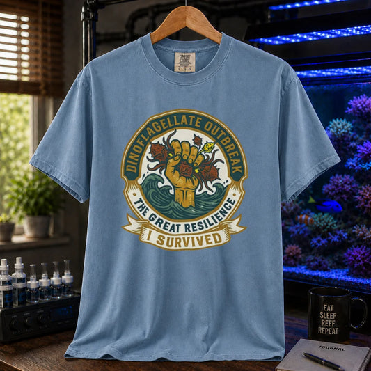 Saltwater aquarium graphic t-shirt featuring a retro survival badge illustration and text: DINOFLAGELLATE OUTBREAK THE GREAT RESILIENCE I SURVIVED, blue crew neck tee
