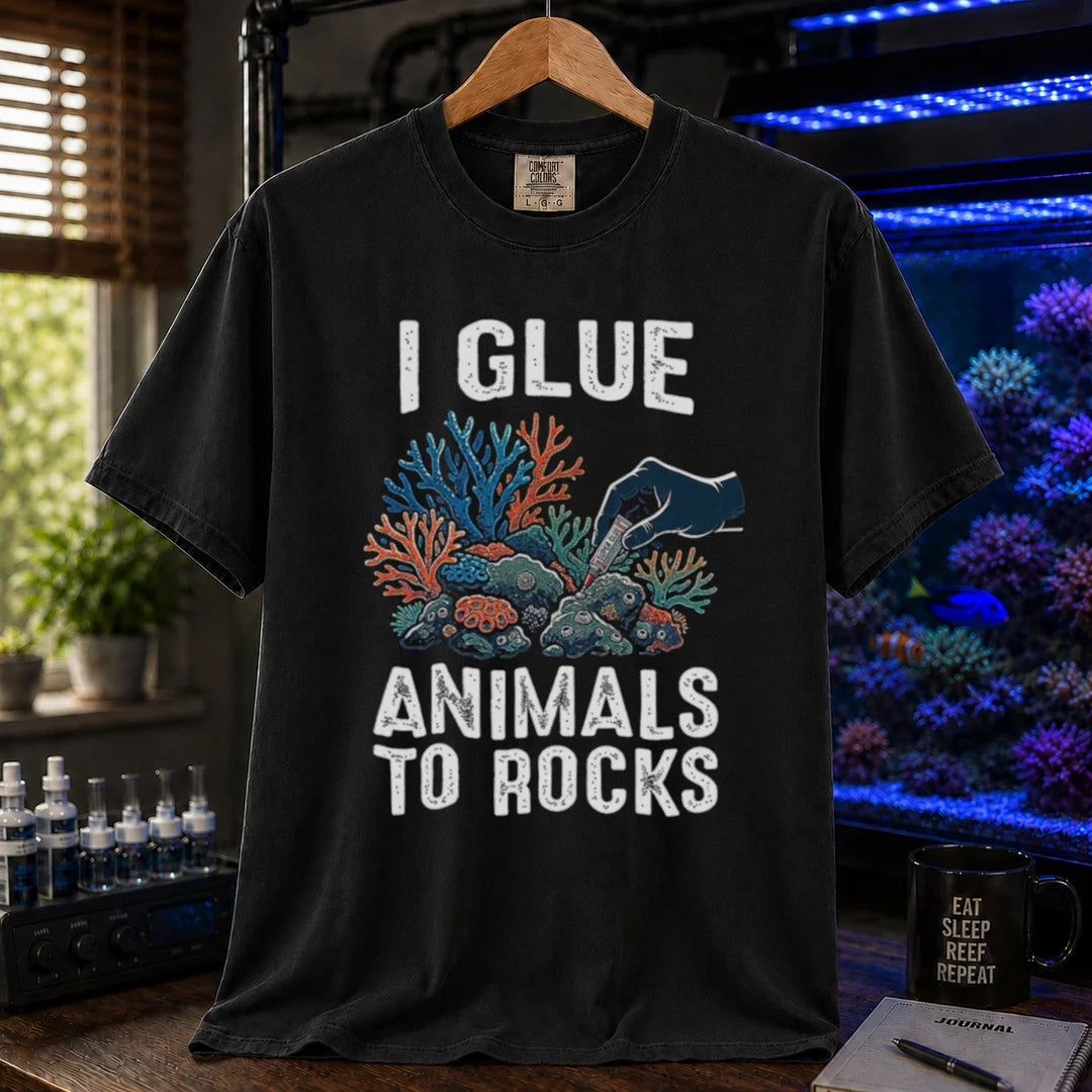 Saltwater aquarium graphic t-shirt featuring a hand gluing coral to rock illustration and text: I GLUE ANIMALS TO ROCKS, black crew neck tee