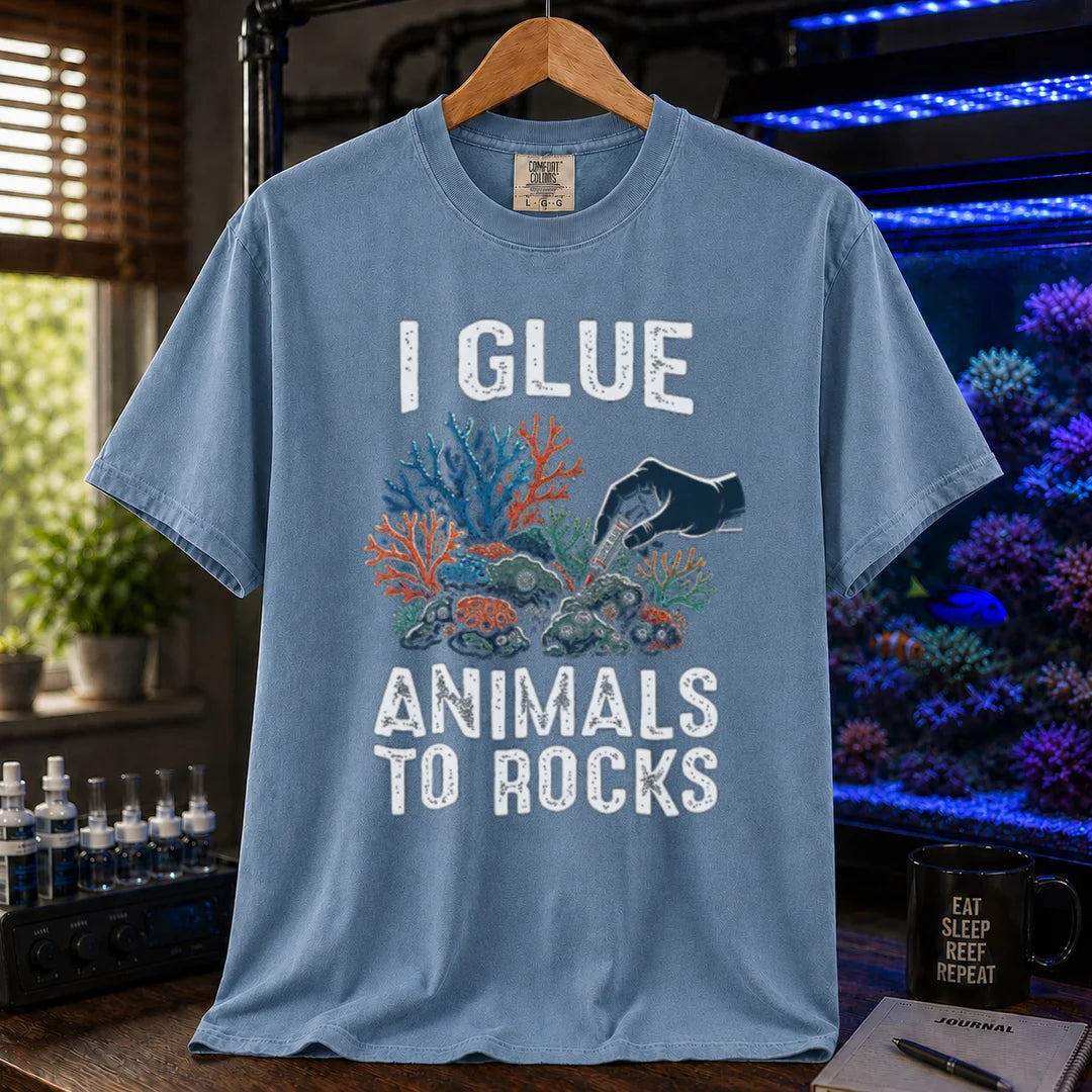 Saltwater aquarium graphic t-shirt featuring a hand gluing coral to rock illustration and text: I GLUE ANIMALS TO ROCKS, blue crew neck tee