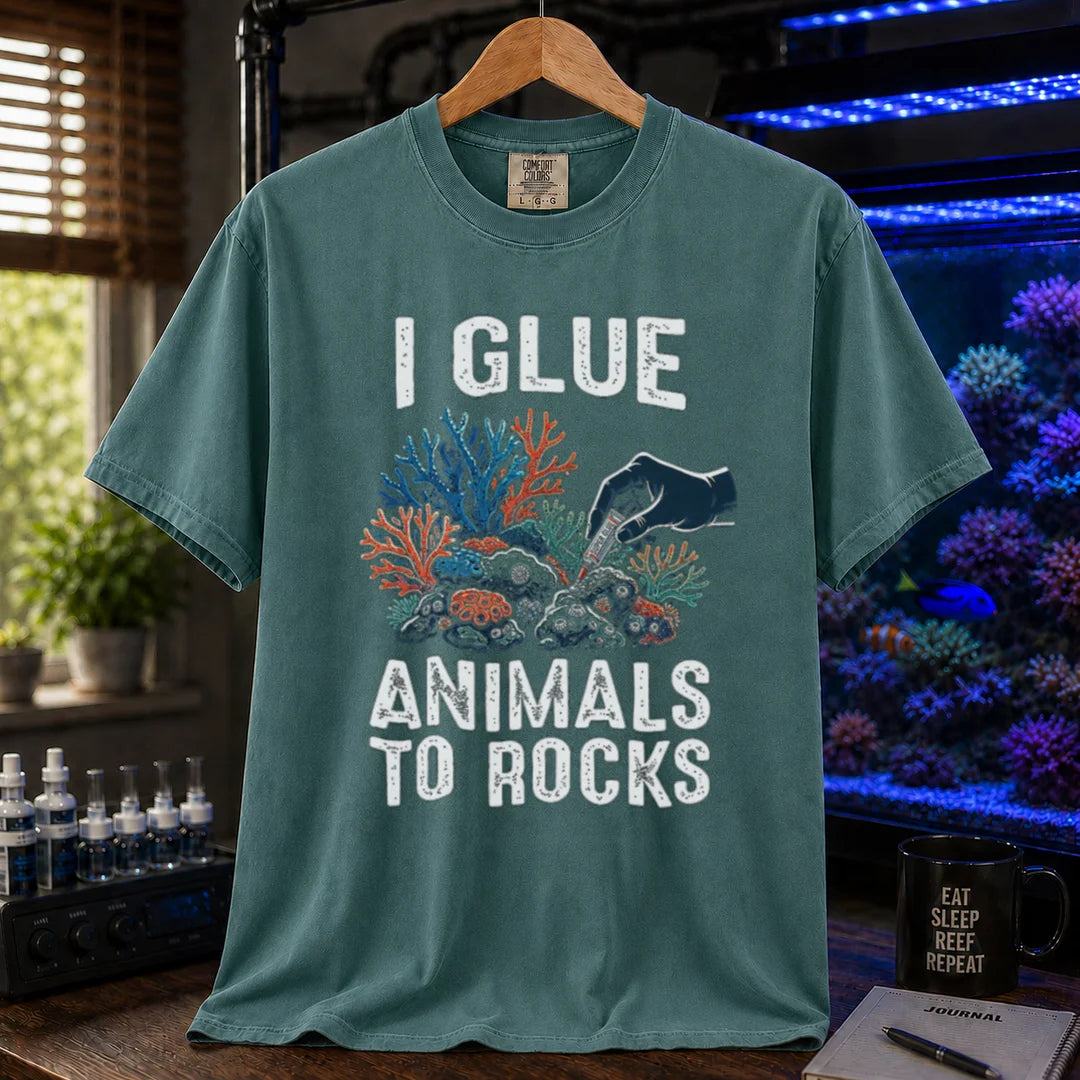 Saltwater aquarium graphic t-shirt featuring a hand gluing coral to rock illustration and text: I GLUE ANIMALS TO ROCKS, green crew neck tee