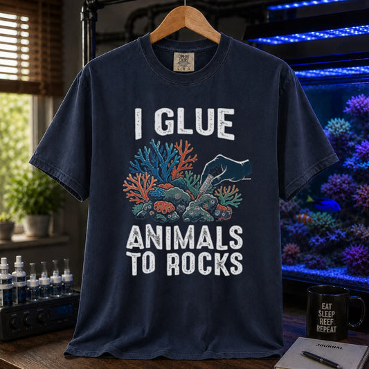 Saltwater aquarium graphic t-shirt featuring a hand gluing coral to rock illustration and text: I GLUE ANIMALS TO ROCKS, navy crew neck tee