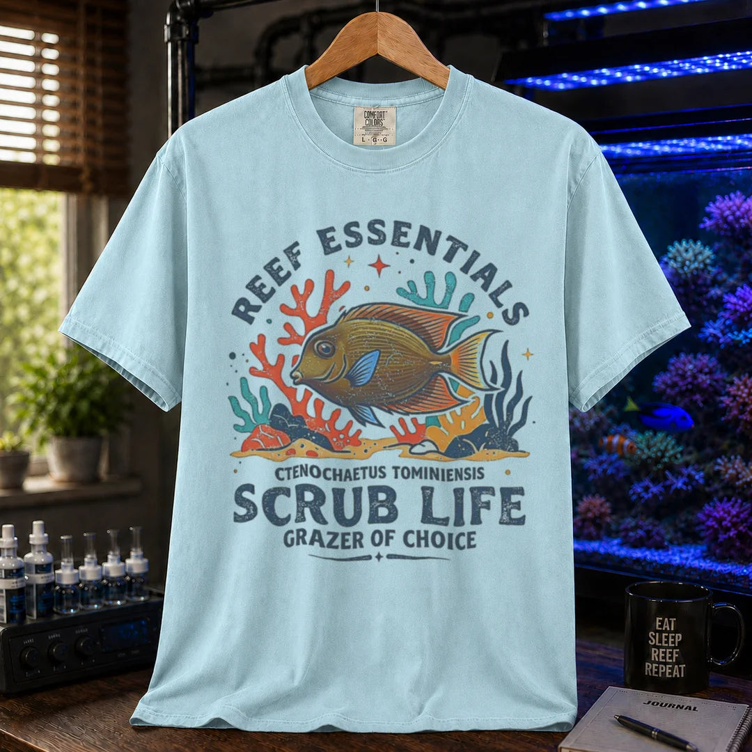 Saltwater aquarium graphic t-shirt featuring a Tomini Tang illustration and text: REEF ESSENTIALS SCRUB LIFE GRAZER OF CHOICE, light blue crew neck tee