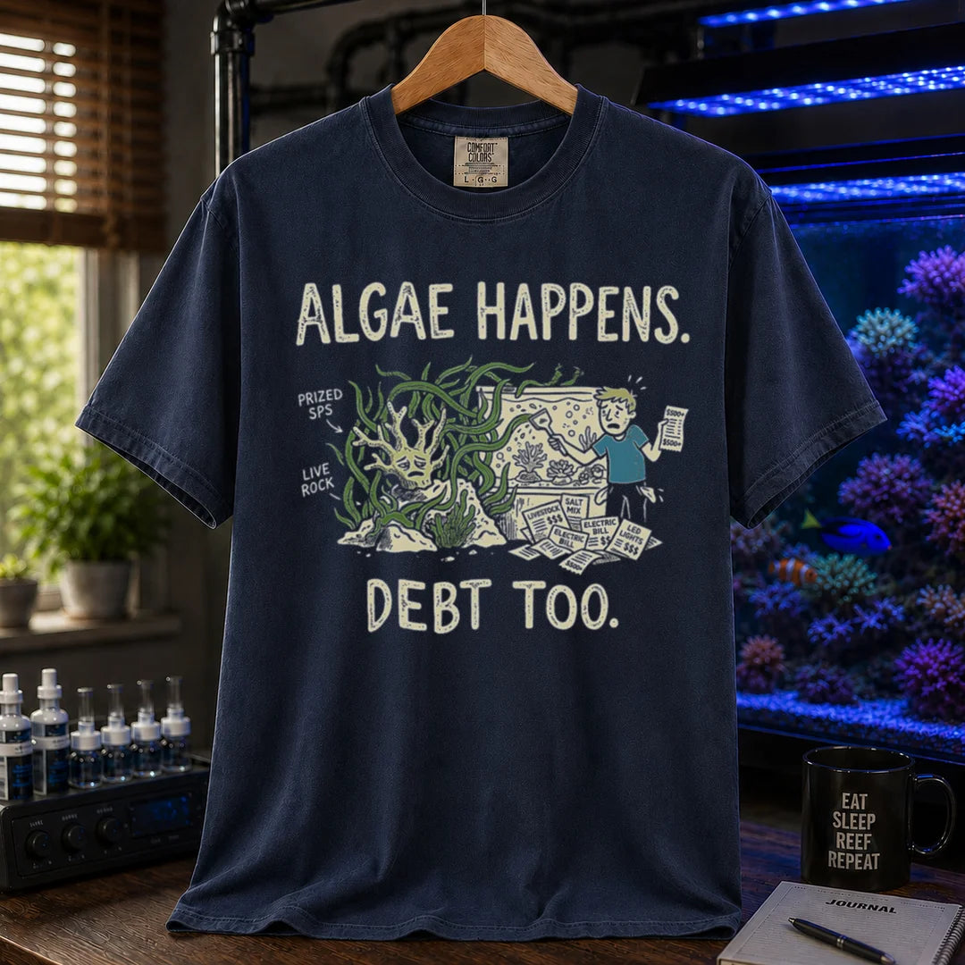 Saltwater aquarium graphic t-shirt featuring an overgrown tank and stressed aquarist illustration with text: ALGAE HAPPENS. DEBT TOO., navy crew neck tee