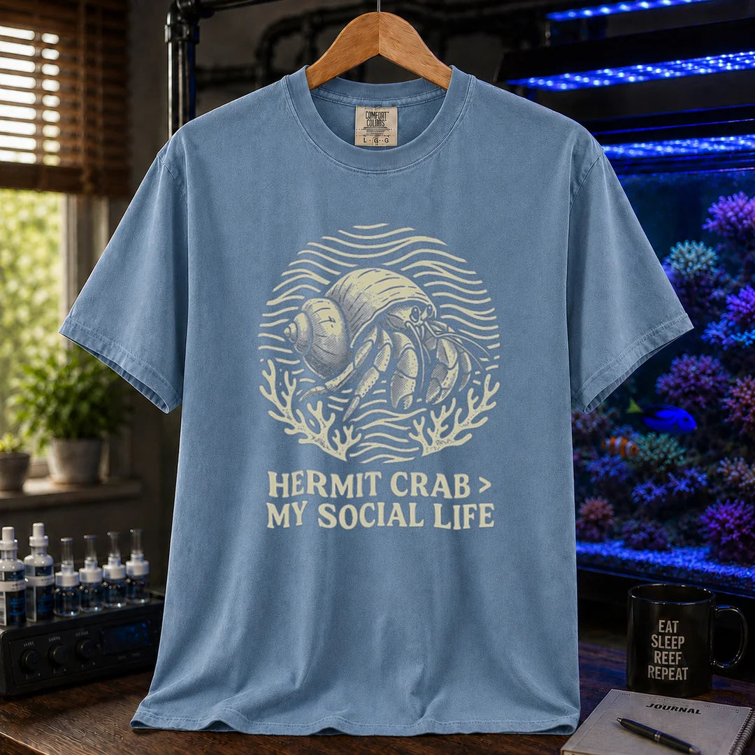 Saltwater aquarium graphic t-shirt featuring a hermit crab illustration and text: HERMIT CRAB > MY SOCIAL LIFE, blue crew neck tee