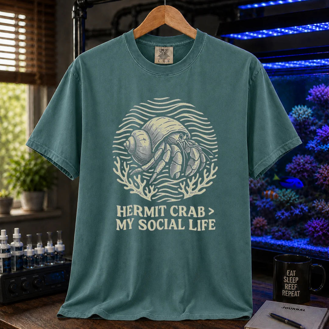 Saltwater aquarium graphic t-shirt featuring a hermit crab illustration and text: HERMIT CRAB > MY SOCIAL LIFE, green crew neck tee